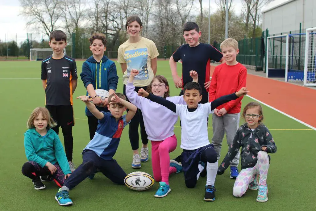 Children of various ages on an all weather pitch looking happy and striking a pose!